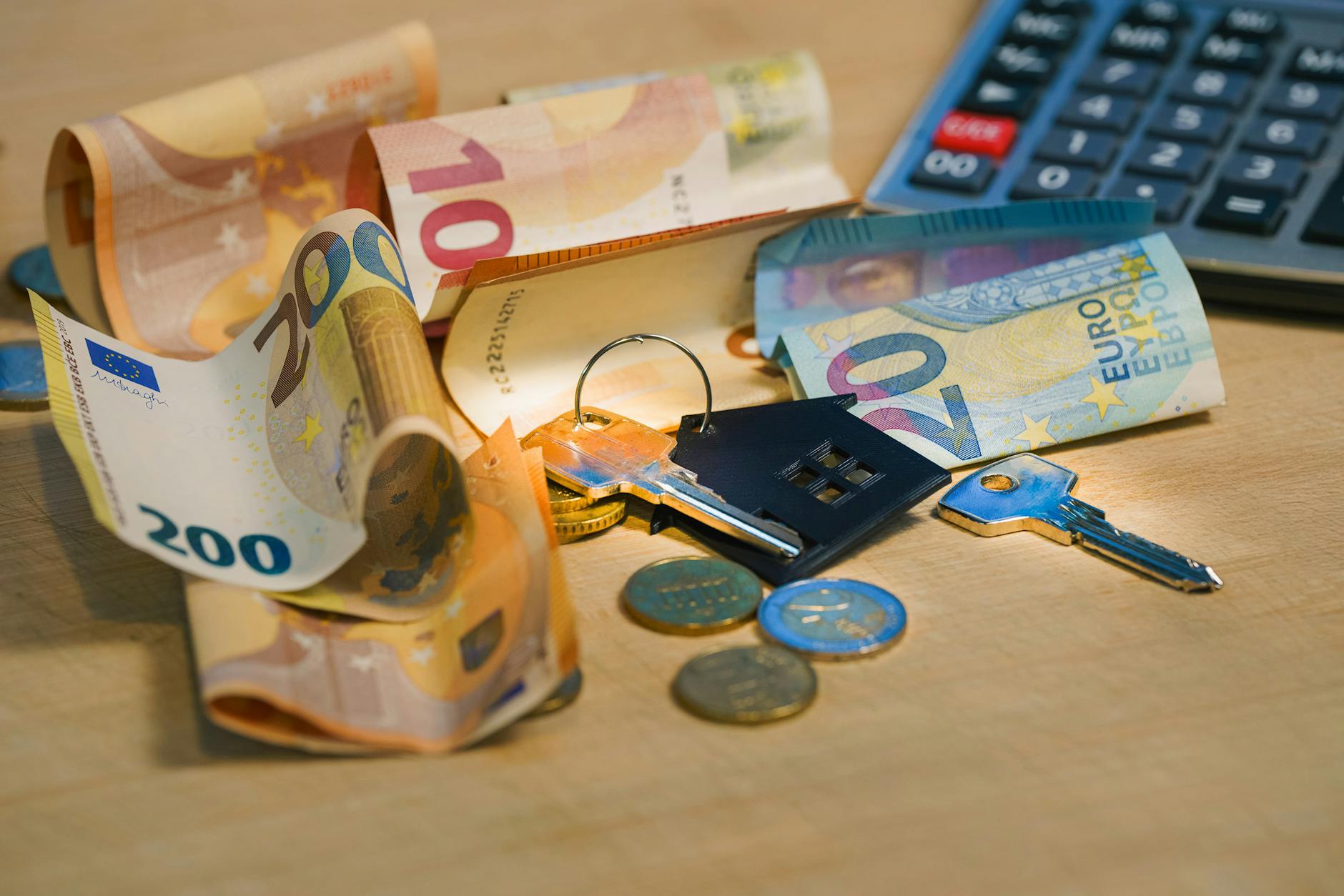 euro banknotes and keys on wooden surface